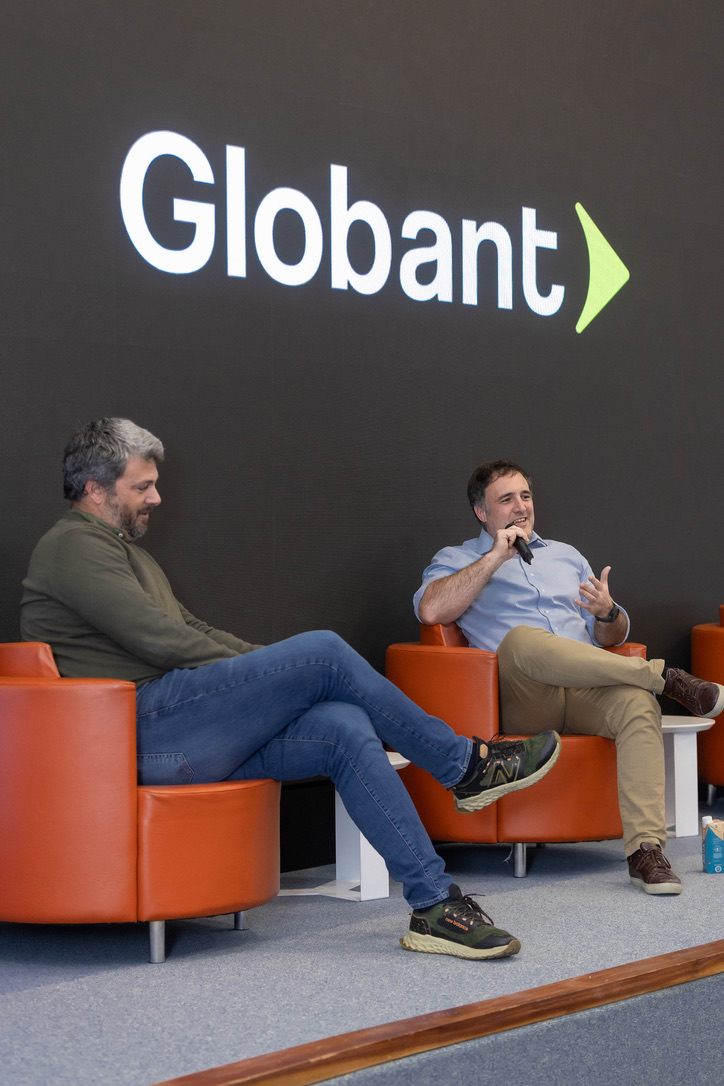 Federico Gottfried y Gregorio Lascano, de Globant, conversando sentados en sillones frente a la pantalla con el logo de Globant